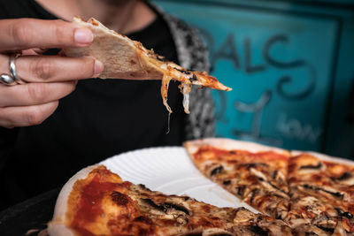 Midsection of woman having pizza in plate