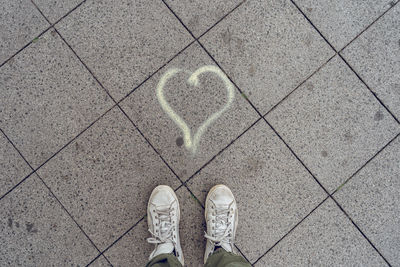 Low section of man standing by heart shape on footpath