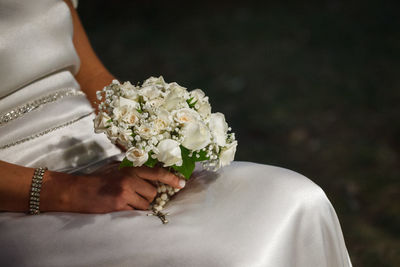 Midsection of bride holding bouquet and rosary beads at wedding