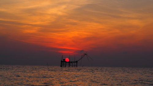 Silhouette lifeguard hut on beach against sky during sunset