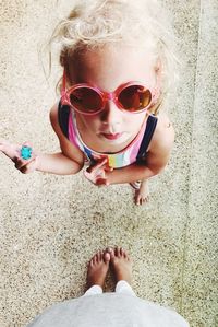 Low section of mother standing with daughter wearing sunglasses on floor