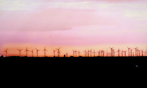 Silhouette of wind turbines in field