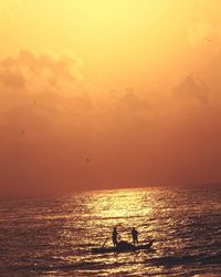 Silhouette men standing on sea against sky during sunset