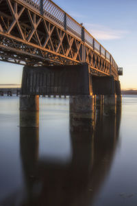 Low angle view of bridge over river against sky