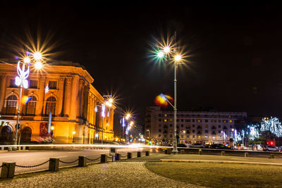 Illuminated street light against building at night