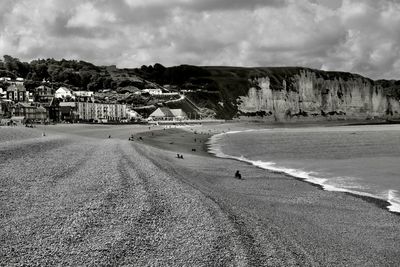 Scenic view of beach by buildings against sky