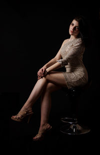 Portrait of woman sitting against black background