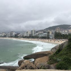 Sea by city buildings against sky