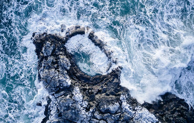 Waves crashing over cliff in sea