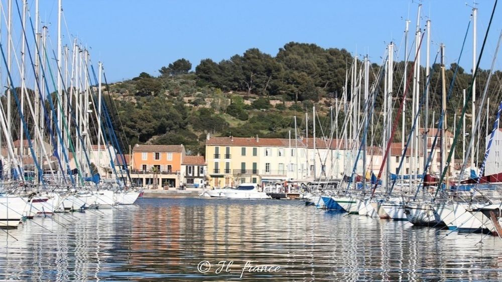 water, nautical vessel, moored, waterfront, harbor, transportation, blue, built structure, building exterior, architecture, boat, in a row, reflection, mode of transport, sea, panoramic, palm tree, mast, day, sailboat