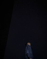 Rear view of woman standing against dark sky