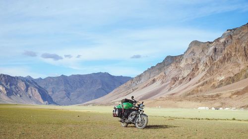 Man riding bicycle on road against mountain range