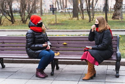 Woman sitting on bench in park during winter