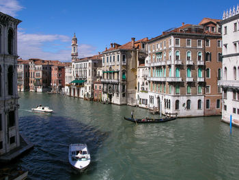 Boats in canal amidst buildings in city