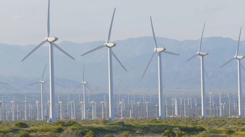 Wind turbines on field against sky