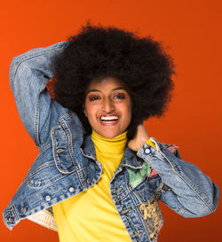 Portrait of happy young woman standing against red background