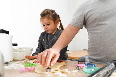 Daughter helping father preparing food in kitchen at home