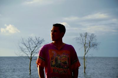 Young man standing against lake