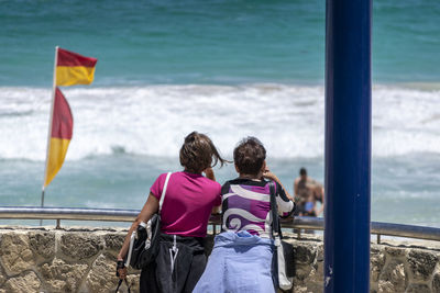 Rear view of women walking on sea shore