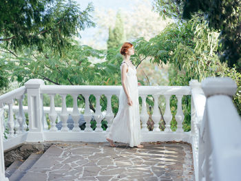 Woman standing by railing against trees