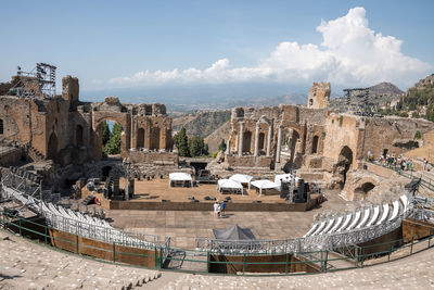 Tourists exploring old ruins of greek theater during summer vacation