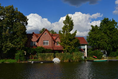 Houses by river against sky