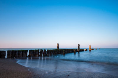 Pier over sea against clear blue sky