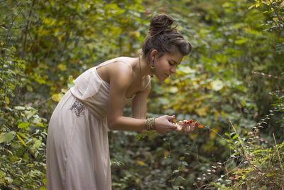 Woman standing by tree against plants