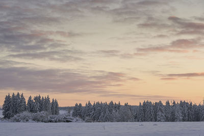 Scenic view of frozen landscape against sky during sunset