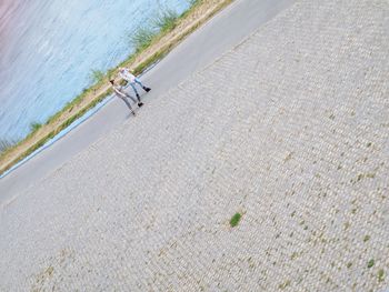 High angle view of people walking on road by sea