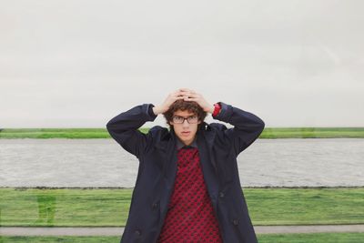 Portrait of teenage boy standing against river