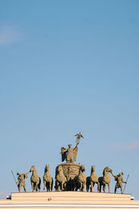 Low angle view of statues against clear blue sky