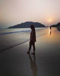 Woman on beach against sky during sunset