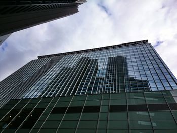 Low angle view of modern building against cloudy sky