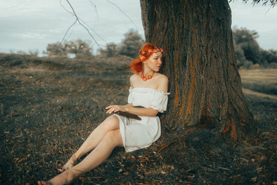 Young woman sitting on tree trunk