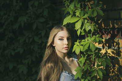 Portrait of beautiful young woman standing by plants in park