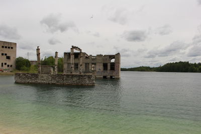 View of buildings at waterfront against cloudy sky