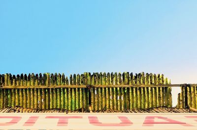 Row of fence against clear blue sky