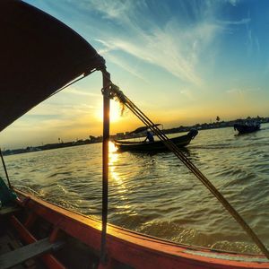 Boats in sea at sunset