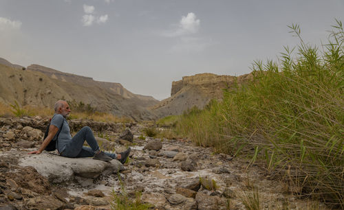 Adult man sitting on rock on tabernas desert in almeria, spain