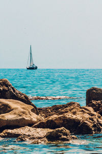 Sailboat sailing on sea against clear sky