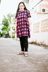 Full length portrait of smiling young woman standing outdoors