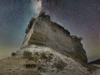 Low angle view of rock formation against sky at night