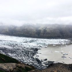 Scenic view of lake by mountains against sky