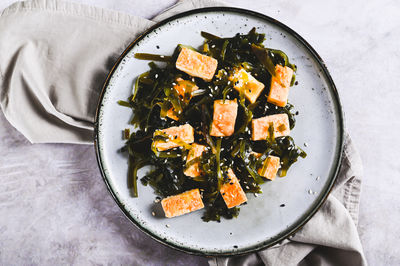 Close up of vegetarian fried tofu and seaweed salad on a plate on the table top view