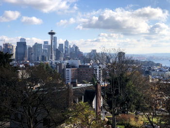 Trees and buildings in city against sky