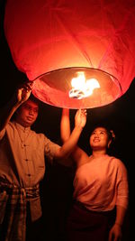 Man and woman holding paper lantern at night