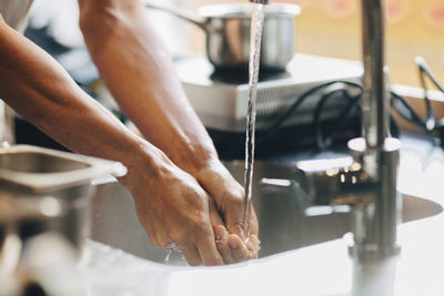 Cropped image of male chef washing hands in sink at commercial kitchen