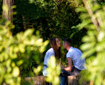 Rear view of couple kissing against trees