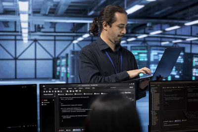 Side view of man using laptop at office